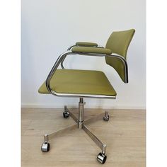 a green office chair sitting on top of a wooden floor next to a white wall