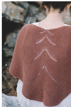 a woman wearing a brown knitted shawl with an arrow pattern on the back