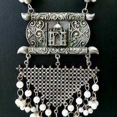 German silver Indian pendant necklace with Taj Mahal in 3D, and a beautiful geometric pendant with faux pearl dangling ghungroo. In a soft grey color with the patina of a vintage piece. Realistic faux pearls Excellent quality and craftsmanship. Necklace measures 12 inch drop. Pendant measures 4.5 inches by 3 inches. View more necklaces here: https://www.etsy.com/shop/BoutiqueByMaryam?section_id=21694658 Be sure to visit the rest of my shop here: https://www.etsy.com/shop/boutiquebymaryam Traditional White Oxidized Finish Necklace, Traditional White Necklace With Oxidized Finish, Traditional White Necklaces With Oxidized Finish, Festive Bohemian Pearl Necklace, Silver Temple Necklace In Metal, Traditional Silver Dangle Necklaces, Bohemian White Necklaces With Latkans, White Bohemian Necklaces With Latkans, Silver Bohemian Pearl Necklace