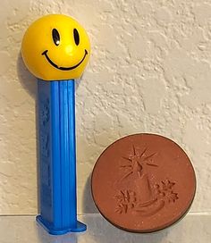 a penny sitting next to a smiley face eraser on a white counter top,