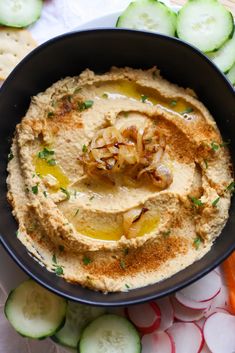 hummus in a bowl surrounded by sliced cucumbers