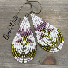 the beaded earrings are hanging from hooks on a wooden surface with an inscription that reads,