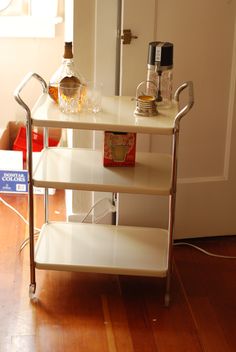 a three tiered serving cart with bottles on it