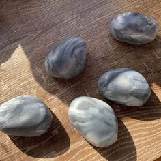 four rocks sitting on top of a wooden table covered in white and gray paint,