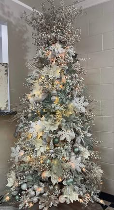 a white christmas tree with silver ornaments and lights