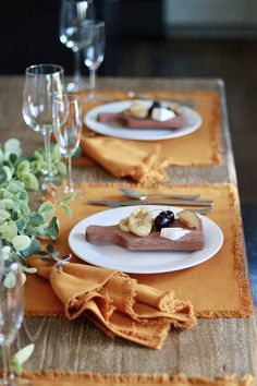 two plates with desserts on them sitting on a table next to some wine glasses