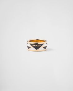 The iconic triangle, the distinctive signature of Prada collections, is transformed into a geometric pattern that embellishes this enameled metal ring. The accessory with sleek, contemporary lines is decorated with the lettering logo that completes the band style with an iconic note. Prada Ring Gold, Prada Rings, Prada Gold Necklace, Prada Symbole Earrings, Luxury Yellow Gold Signet Ring With Black Enamel, Coffee Line, Prada Jewelry, Porcelain Candle, Prada Collection