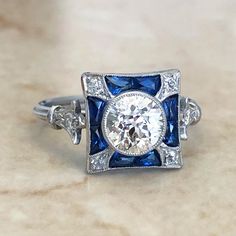 Gorgeous Art Deco style diamond and sapphire engagement ring handcrafted in platinum. It centers a fine old European cut diamond weighing 1.02 carat approximately I-J color VS clarity. 8 blue sapphires surround the center stone. The ring is accented with 0.10 carat of old cut diamonds. Ring size 6.75 US. Birthstone: April/September Condition: Excellent. Brand New. - 14 day return policy, no questions asked. - Free insured shipping in the US. - International shipping available. - Courtesy ring si Diamond White Sapphire Diamond Ring With Center Stone, Diamond White Sapphire Ring With Center Stone For Gift, White Sapphire Diamond Ring With Center Stone, White Sapphire Ring With Center Stone As Gift, Diamond White Sapphire Princess Cut Jewelry, Diamond White Sapphire Jewelry With Princess Cut, Princess Cut Diamond White Sapphire Jewelry, Princess Cut Sapphire Jewelry In Diamond White, Diamond White Lab-created Sapphire Ring With Center Stone