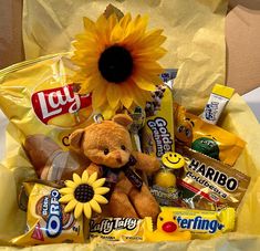 a teddy bear sitting in a yellow bag filled with candy and candies next to a sunflower