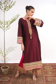 A maroon, raw silk, Kashmiri cut long kurta with Marori lace on the neck and sleeves. A pink tissue silk ajar pant lends a royal look to the suit. Finished with a matching tissue organza dupatta with pink border. 3-piece suit Ready to wear Bollywood Cotton Silk Palazzo Set With Embroidered Border, Traditional Drape Art Silk Palazzo Set With Embroidered Border, Traditional Embroidered Art Silk Palazzo Set, Eid Slub Silk Sets With Embroidered Border, Diwali Embroidered Raw Silk Palazzo Set, Festival Tissue Silk Straight Kurta, Eid Tissue Silk Straight Kurta, Tissue Silk Palazzo Set With Traditional Drape For Eid, Eid Tissue Silk Palazzo Set With Traditional Drape