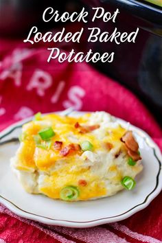 crock pot loaded baked potatoes on a white plate with green onions and bacon in the background