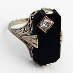 "Vintage 14 K (.585) white gold long ring, having open-work floral design setting with chamfered rectangle form Onyx centerpiece, accented with Diamond inset. The Diamond is 0.23ct., color J, SI1 clarity. This impressive ring is a size 8, 13/16\" long and weighs 3.2 grams. EA1807"