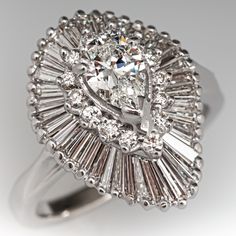 This exquisite ring features a 18K white gold gallery and is finished with a 14K white gold shank. The ring is centered with one (1) pear shape diamond center in a three-prong setting. The center is surrounded by fourteen (14) prong set, round brilliant cut diamonds and forty (40) prong set, tapered baguette cut diamonds. The ring measures 20mm at the top, rises 11.21mm above the finger, tapering to 2.23mm wide and 2.16mm thick at the base of the shank. This ring is currently a size 8.5. Diamond Cocktail Ring, Pear Cut Diamond, Diamond Cocktail Rings, Baguette Cut Diamond, Amethyst Jewelry, Ring Pendant, Platinum Ring, Pear Shaped Diamond, Diamond Set