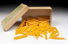 a box filled with yellow candles sitting on top of a white table next to a cardboard box