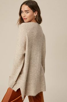 So chic and effortless, this slouchy, oversized tunic-style sweater features a v-neckline and dropped wide sleeves for added shape. -Available in Stone & Misty Blue -Waffle textured -V-neck -Oversized fit -Soft touch eyelash two tone yarn -Long sleeve with folded cuffs -Side slits -Ribbed on hem -Content: 74% Acrylic 22% Polyester 4% Lycra -Hand was cold/Line dry -Imported -Model is 5 8" 32-24-34 and wearing a size Small Oversized V-neck Sweater For Layering, Oversized Chic V-neck Sweater, Oversized V-neck Sweater For Fall, Oversized V-neck Chic Sweater, Beige V-neck Sweater For Fall Loungewear, Oversized V-neck Sweater For Loungewear, Oversized Chic Sweater With Ribbed Neckline, Chic Oversized V-neck Sweater For Loungewear, Relaxed Fit V-neck Knit Cardigan