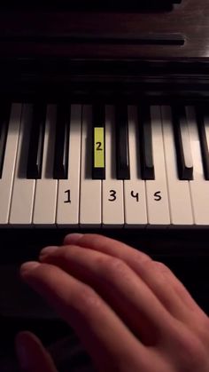 a person's hand is playing the piano with yellow notes on it and black keys