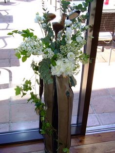 a vase filled with white flowers sitting on top of a wooden floor next to a window