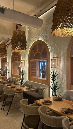 a restaurant with tables, chairs and plants in the center is decorated with straw roofing