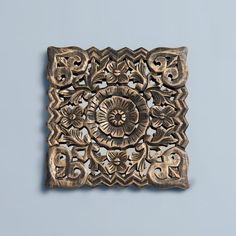 an intricately carved metal object on a blue wall