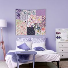 a bedroom with purple walls, white bedding and an art work on the wall