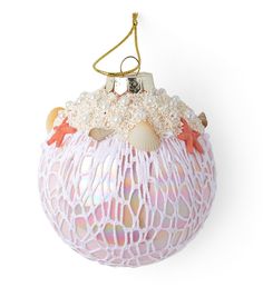 a pink ornament hanging from a gold chain on a white background with pearls and sea shells