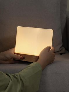 a person sitting on a couch holding a small light in their hand and touching it