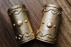 two gold cuffs sitting on top of a wooden table