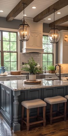 a large kitchen island with stools in front of it and lights hanging from the ceiling