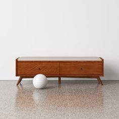 a white ball sitting on top of a wooden table next to a dresser with drawers