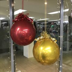 two shiny christmas ornaments hanging from the side of a glass wall in an office building