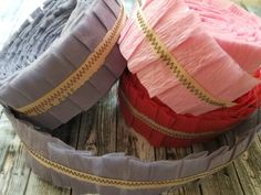 three different colored baskets sitting on top of a wooden table next to each other with ribbons in them