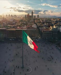 an italian flag flying in front of a cityscape with tall buildings and people walking around