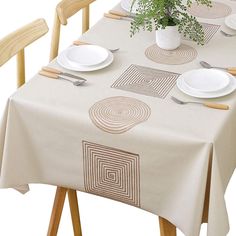 the table is set with white plates and silverware, as well as a potted plant