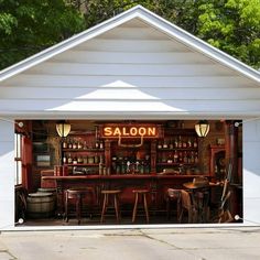 an open garage door showing a bar with stools and bottles on the shelves in front of it