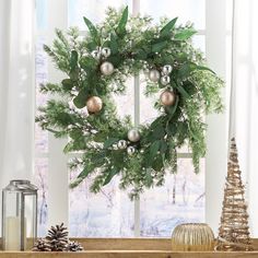 a christmas wreath on a window sill with ornaments and pine cones next to it