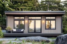 a small house sitting on top of a lush green field next to rocks and trees