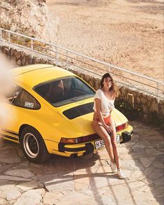 a woman sitting on the hood of a yellow sports car