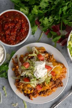 two bowls of chili, lettuce and cheese on a table