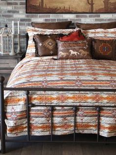 a bed with pillows and blankets on it in front of a brick wall, next to an old dresser