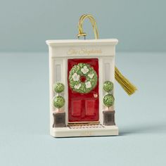 a christmas ornament with a red door and green wreath on it's front