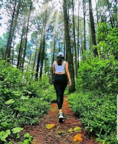 a woman walking down a trail in the woods