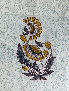 an embroidered piece of cloth with yellow flowers and green leaves on it's side