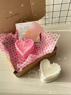 a heart shaped candle in a box next to a cookie