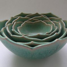 four green bowls are stacked on top of each other in the shape of a flower