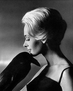 black and white photograph of woman with bird on her shoulder, looking off to the side