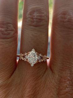 a woman's hand with an engagement ring on it, showing the center stone