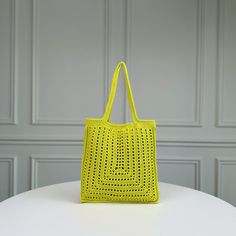 a bright yellow bag sitting on top of a white table next to a gray wall