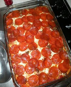 pepperoni and cheese pizza in a baking dish on the stove top next to a measuring spoon