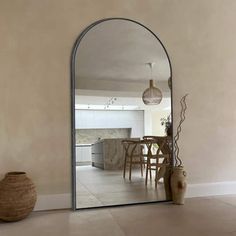 an arched mirror in the middle of a room with a table and vase on the floor