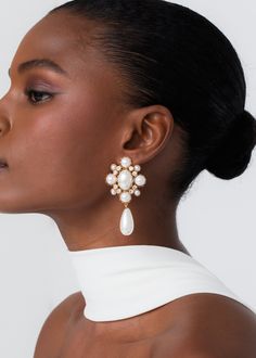 a woman wearing earrings with pearls on the bottom and one earring in gold tone